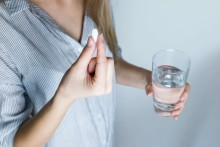 Femme qui consomme un complément alimentaire avec un verre d'eau