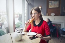 Jeune femme qui mange un croissant dans un café